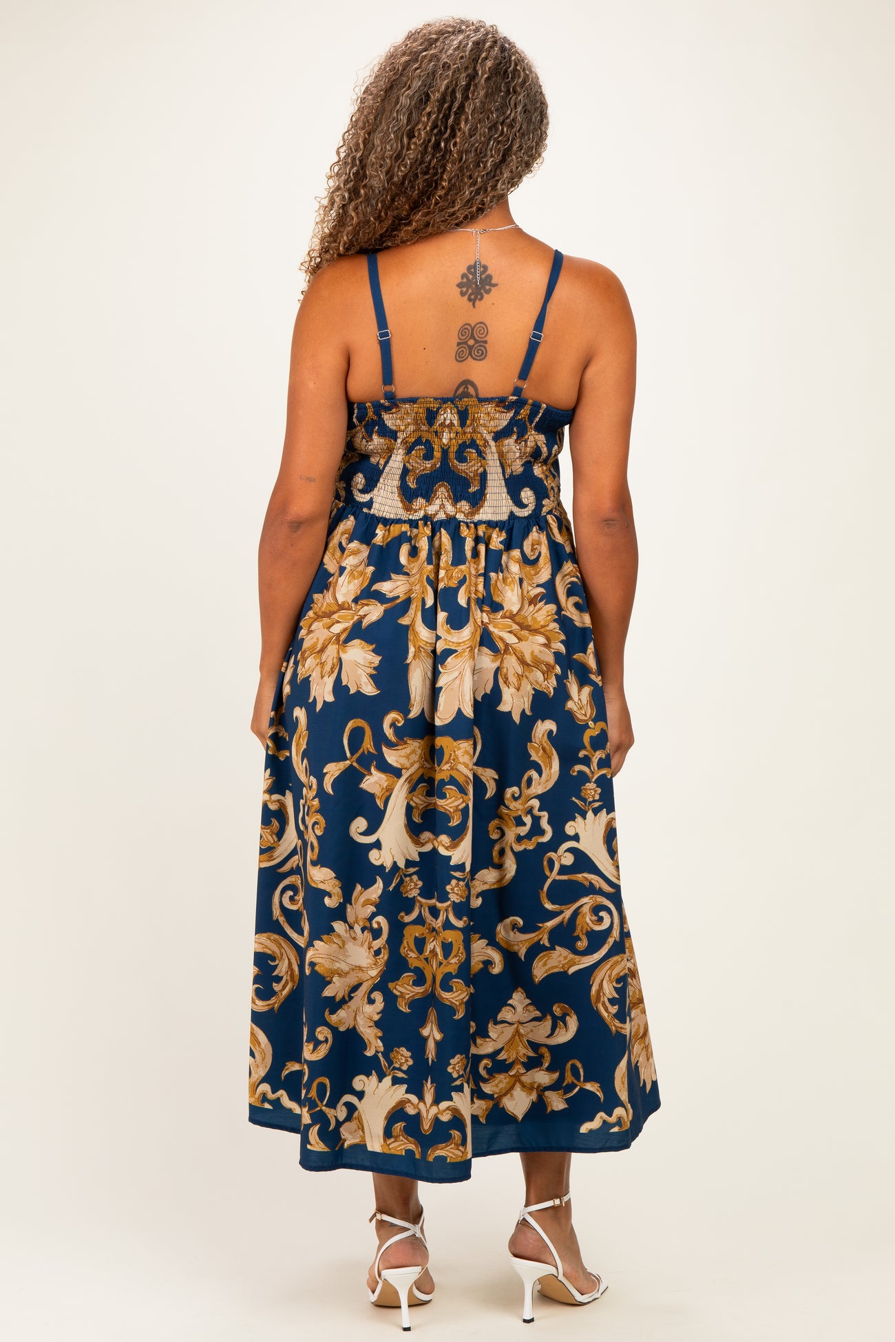 woman wearing a navy blue plus size maxi dress with floral patterns and a smocked back detail