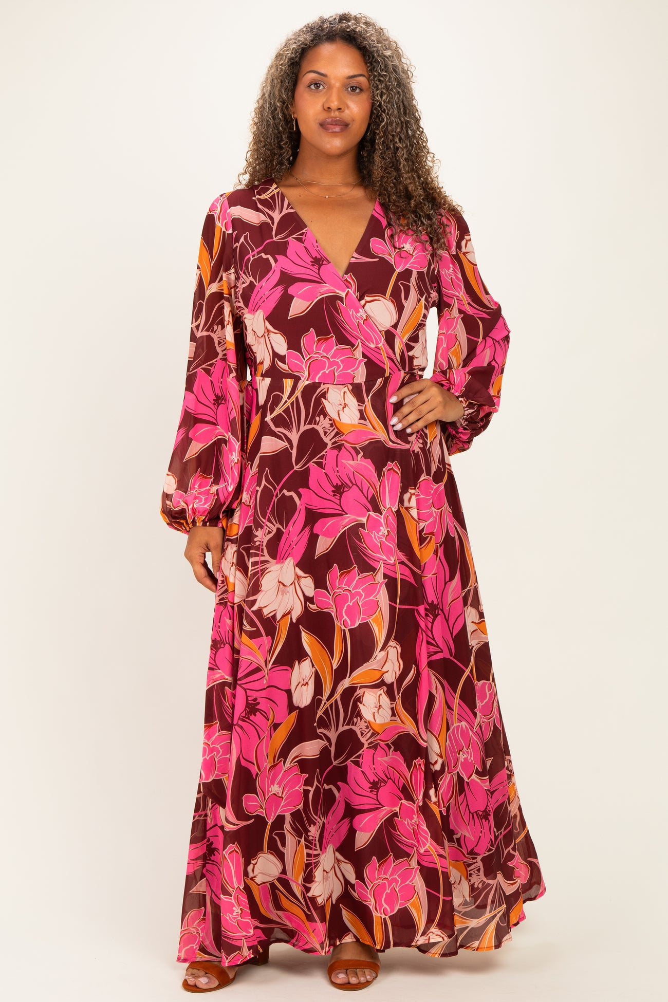 woman wearing a long purple floral plus-size maxi dress with long sleeves and a wrap style