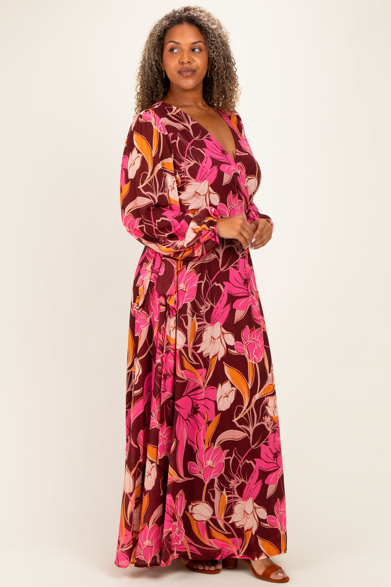 woman wearing a burgundy floral maxi dress with pink and orange flowers and long sleeves