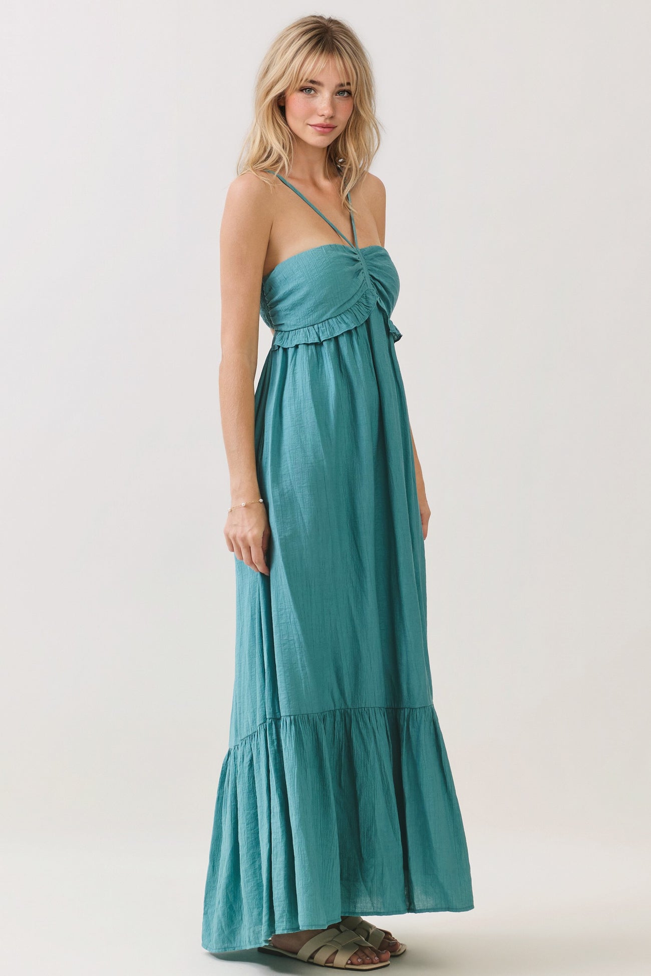 woman wearing a teal strapless maxi dress with a ruffled hem and adjustable ties