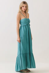 woman wearing a teal strapless maxi dress with a ruffled hem and adjustable ties