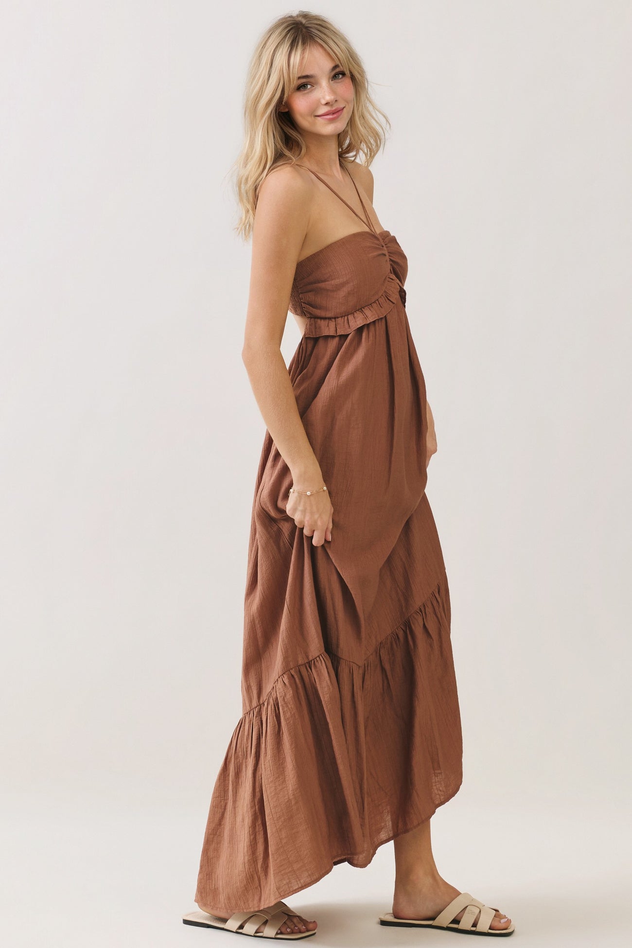 woman wearing a rust-colored strapless maxi dress with a ruffled bodice and tiered skirt