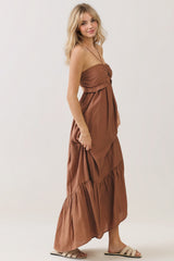 woman wearing a rust-colored strapless maxi dress with a ruffled bodice and tiered skirt