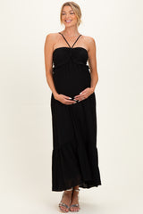 woman wearing a black maternity maxi dress with a gathered bust and spaghetti straps, showing her baby bump