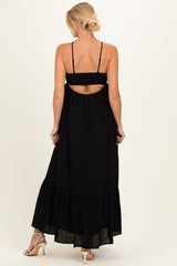 woman wearing a black maternity maxi dress with an open back and tiered hem