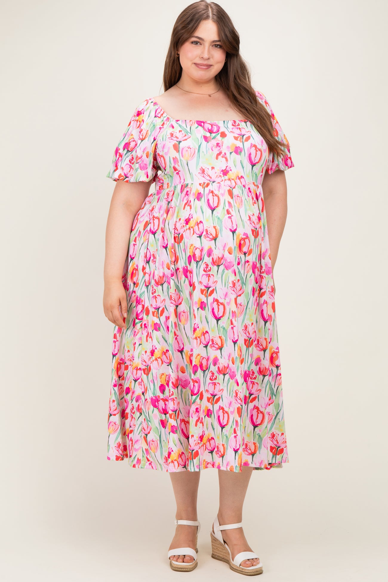 woman wearing a pink floral off-the-shoulder maxi dress, showcasing her baby bump, in maternity plus size