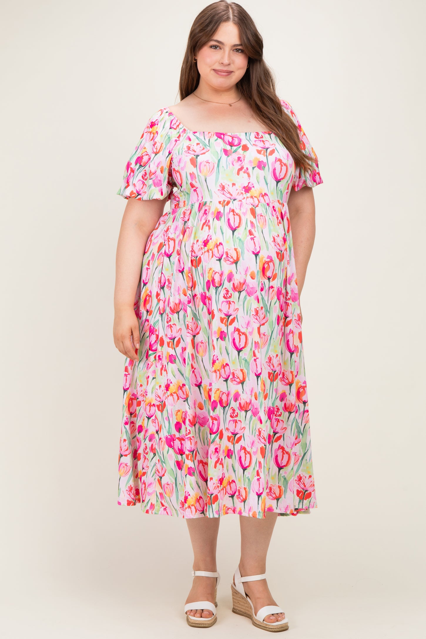 woman wearing a pink floral off-the-shoulder maxi dress, showcasing her baby bump, in maternity plus size