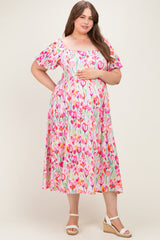 woman wearing a floral maternity plus dress with short puff sleeves and holding her baby bump