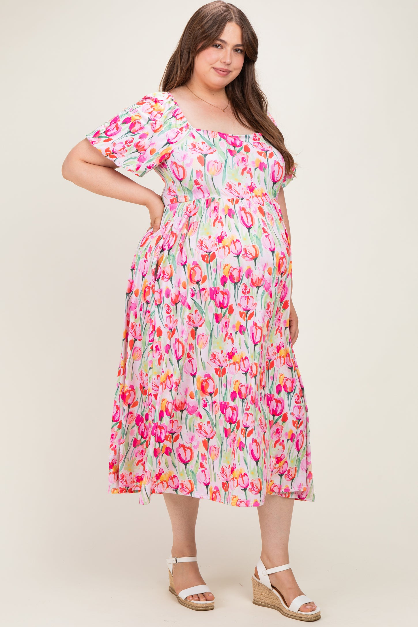 woman wearing a floral maternity plus dress with short sleeves and a square neckline, showing her baby bump