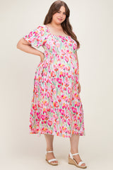 woman wearing a floral maternity plus dress with short sleeves and a square neckline, showing her baby bump