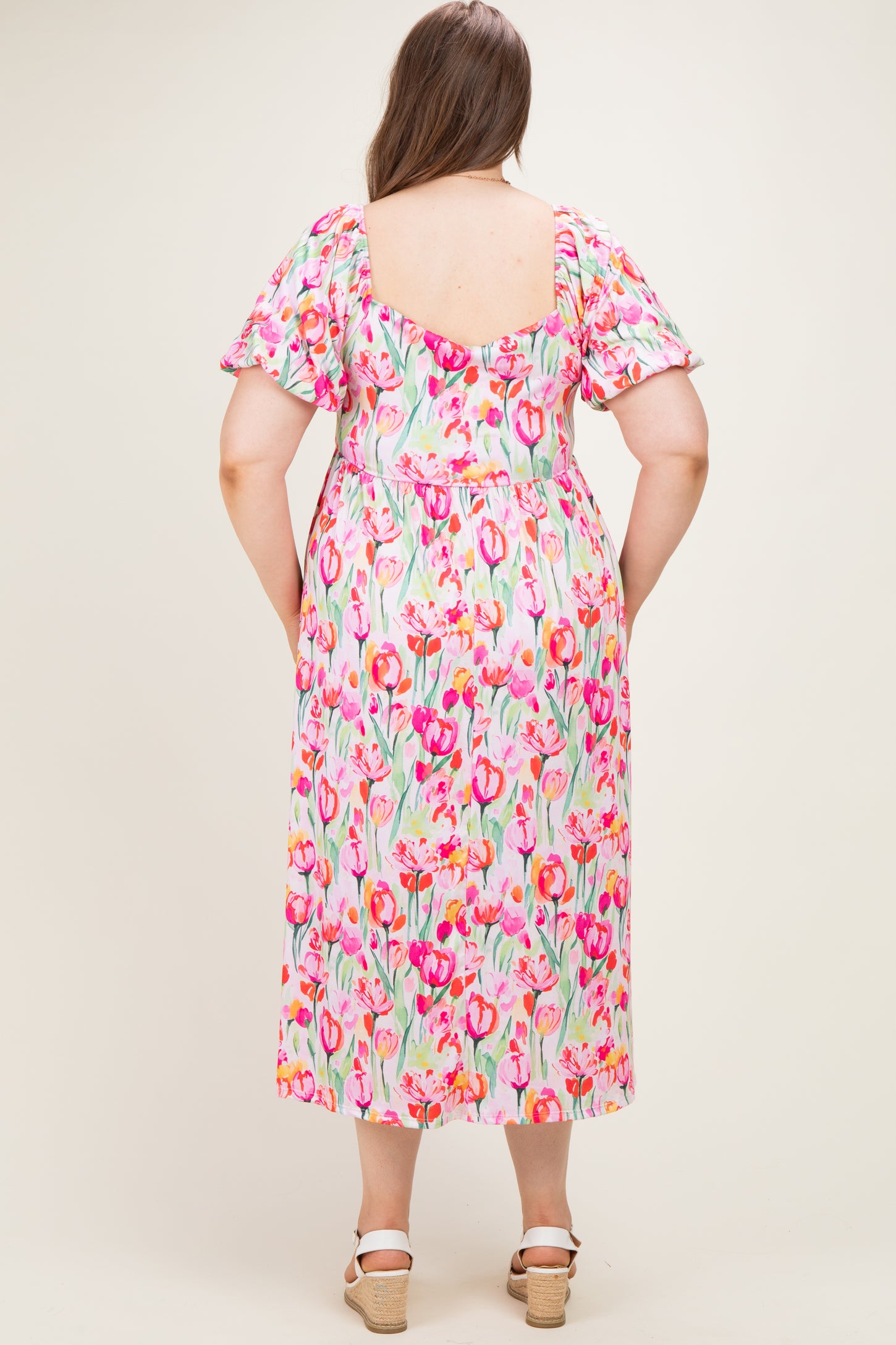 woman wearing a floral print maternity dress with short sleeves, showing the back view and a comfortable loose fit