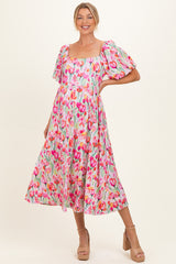 woman wearing a floral print maternity dress with puff sleeves and a square neckline, smiling against a light background