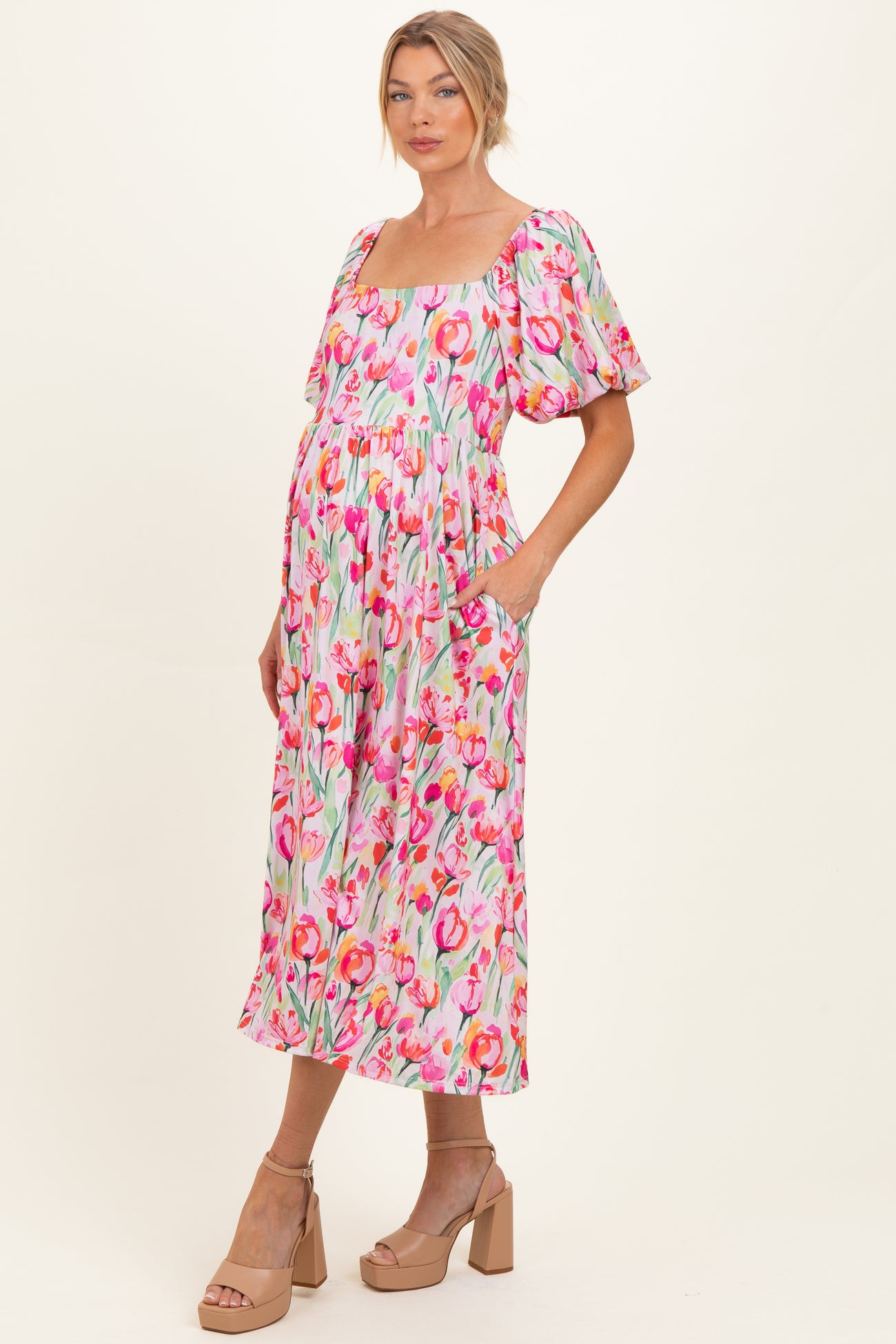woman wearing a floral maternity dress with short puff sleeves and pockets, showcasing her baby bump