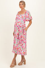 woman wearing a floral maternity dress with short puff sleeves and pockets, showcasing her baby bump