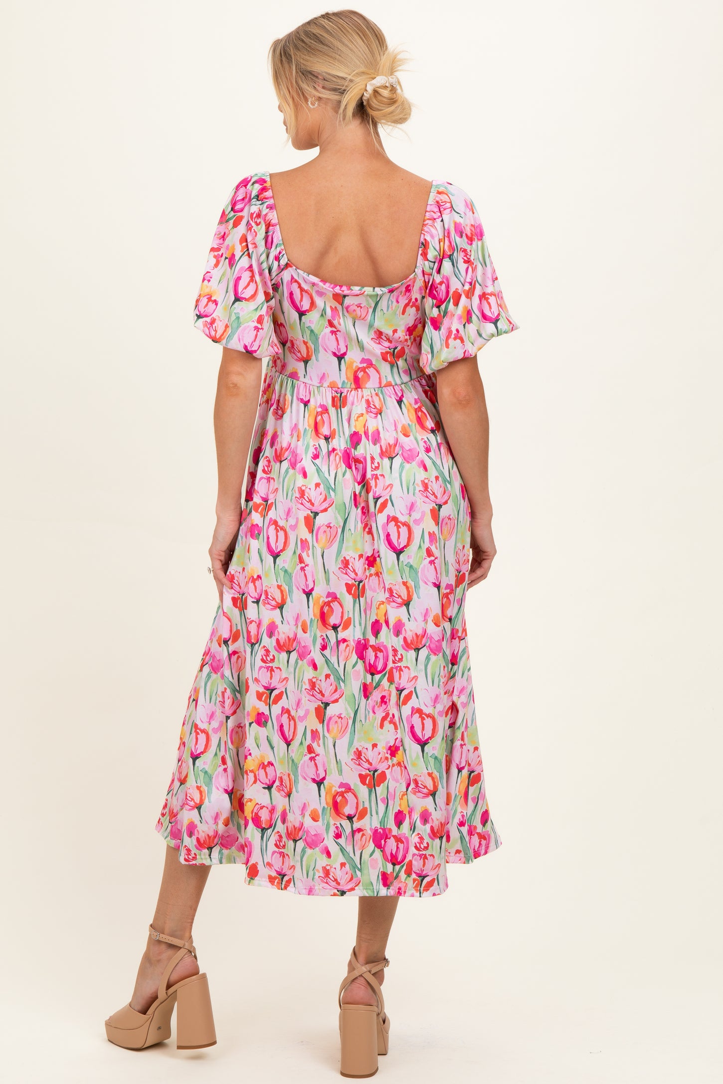 woman wearing a floral print maternity dress with puffed sleeves and a flowy skirt, showcasing a baby bump from the back