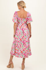 woman wearing a floral print maternity dress with puffed sleeves and a flowy skirt, showcasing a baby bump from the back