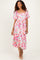 woman wearing a pink floral midi dress with puff sleeves and a square neckline