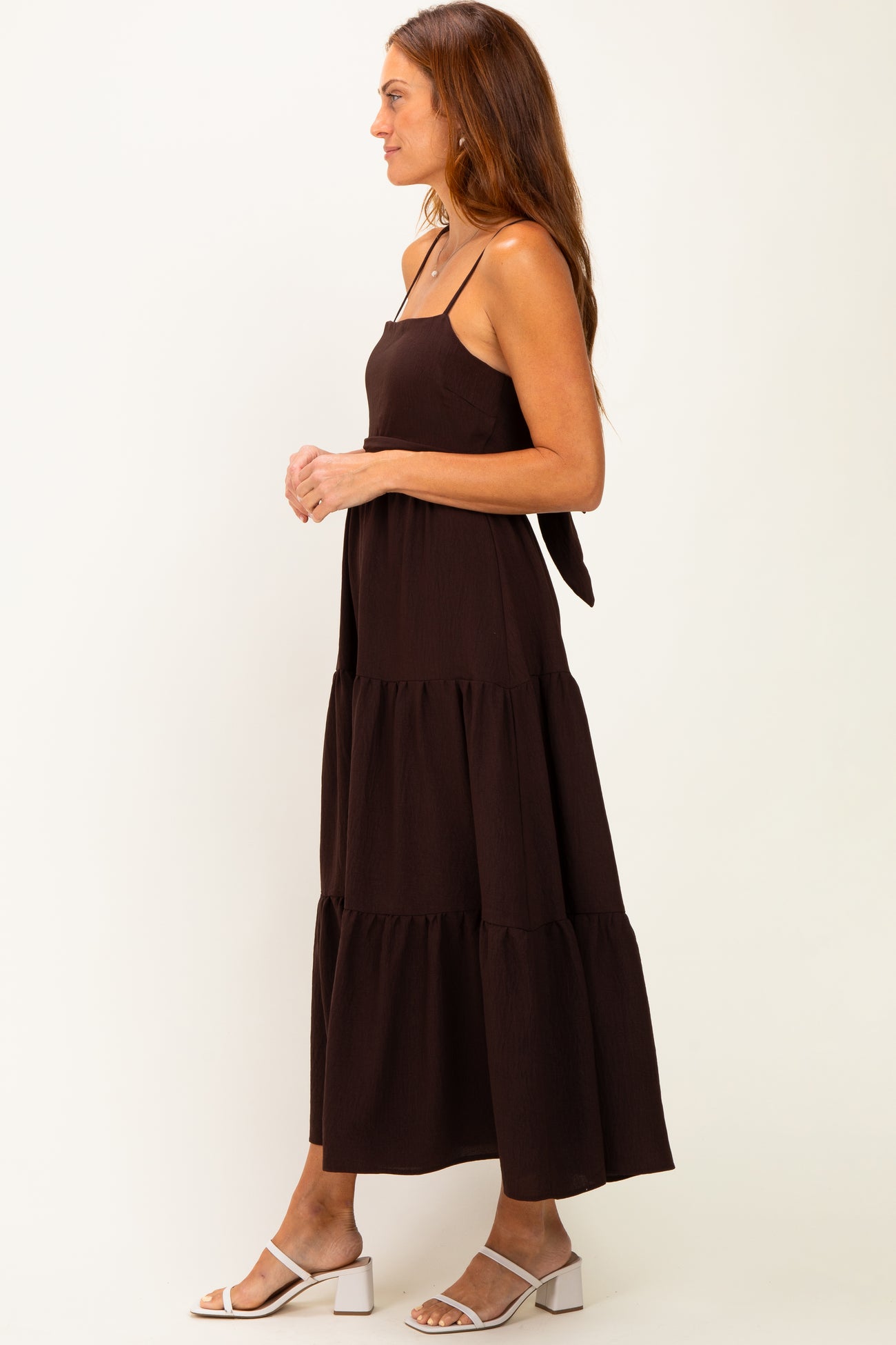 woman wearing a black tiered maxi dress with adjustable straps and a tie detail at the back