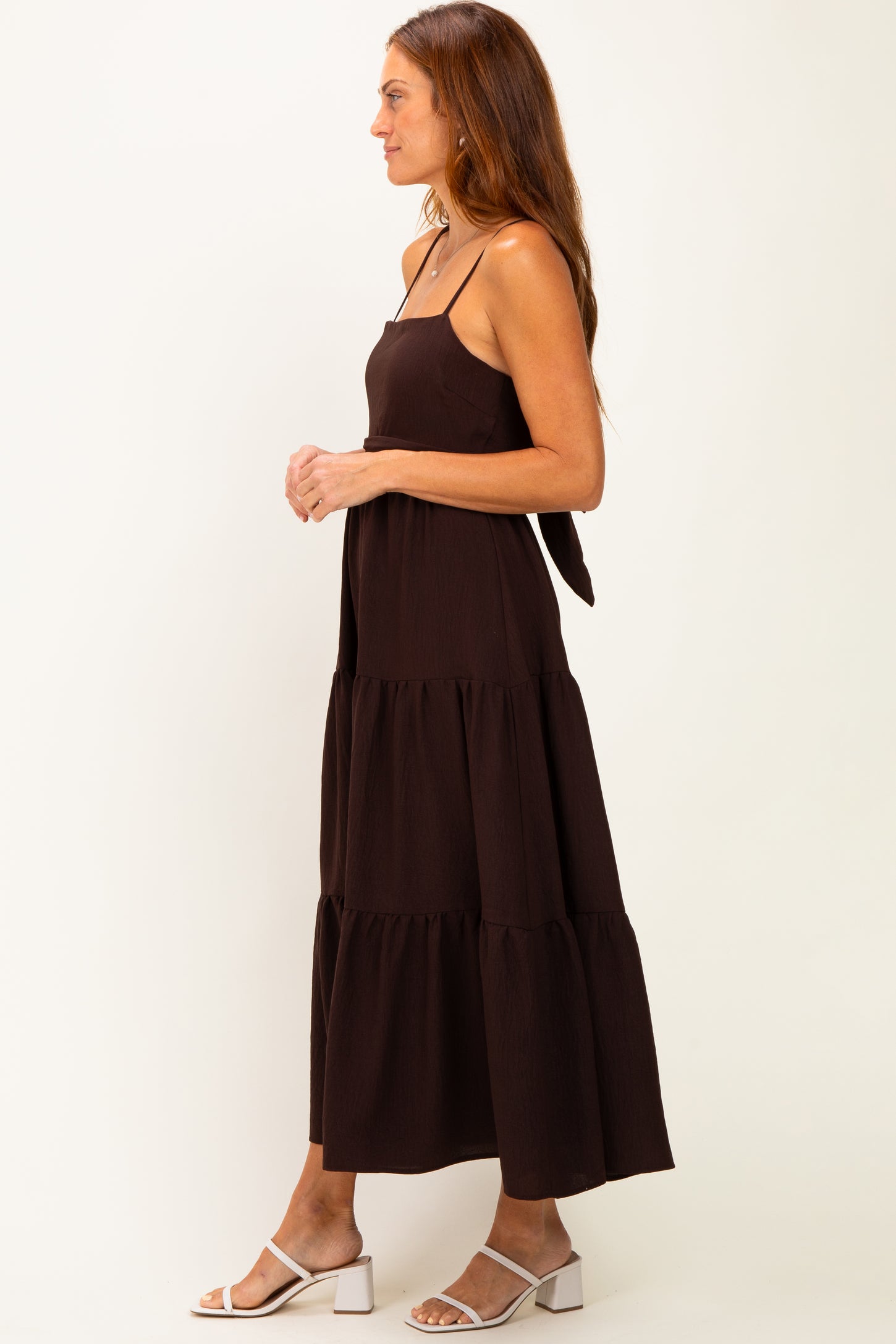 woman wearing a black tiered maxi dress with adjustable straps and a tie detail at the back