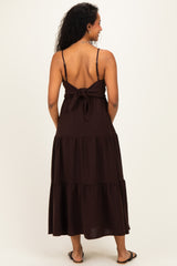 woman wearing a brown tiered maternity maxi dress with a tied back detail and spaghetti straps
