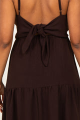 woman wearing a dark brown maternity dress with a tied back detail and flowing tiered skirt, baby bump visible