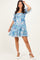 woman wearing a blue floral short dress with puff sleeves and a tiered skirt, standing and smiling