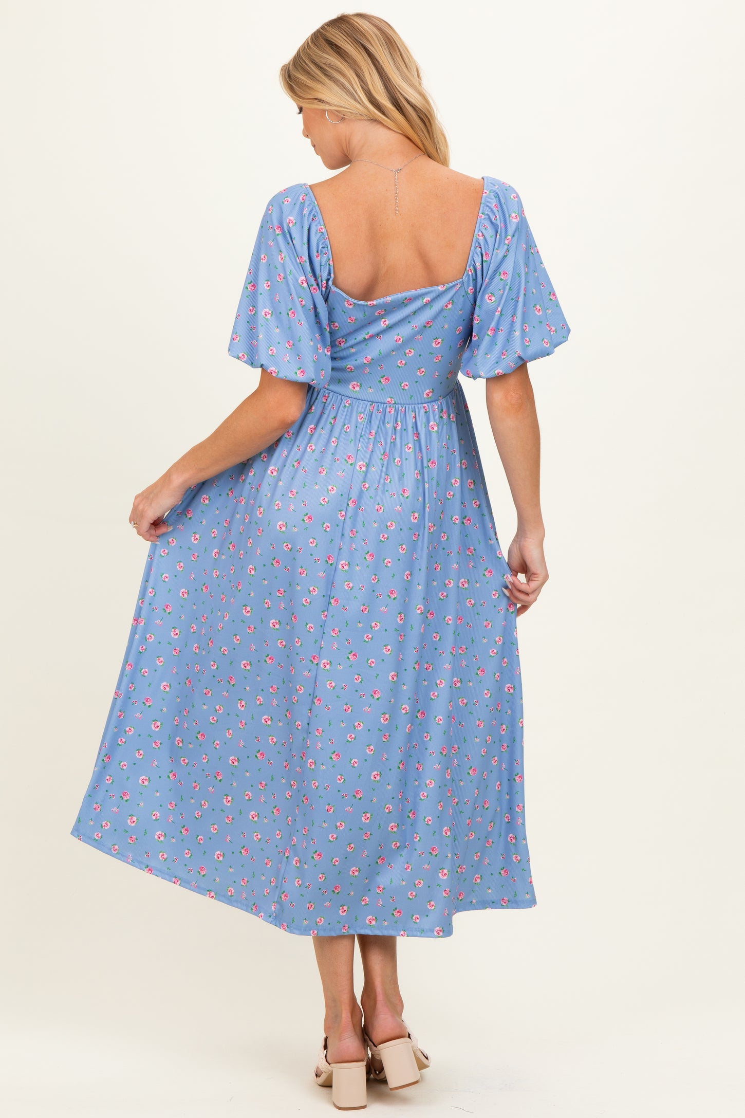 woman wearing a blue floral maternity maxi dress with puff sleeves and an open back