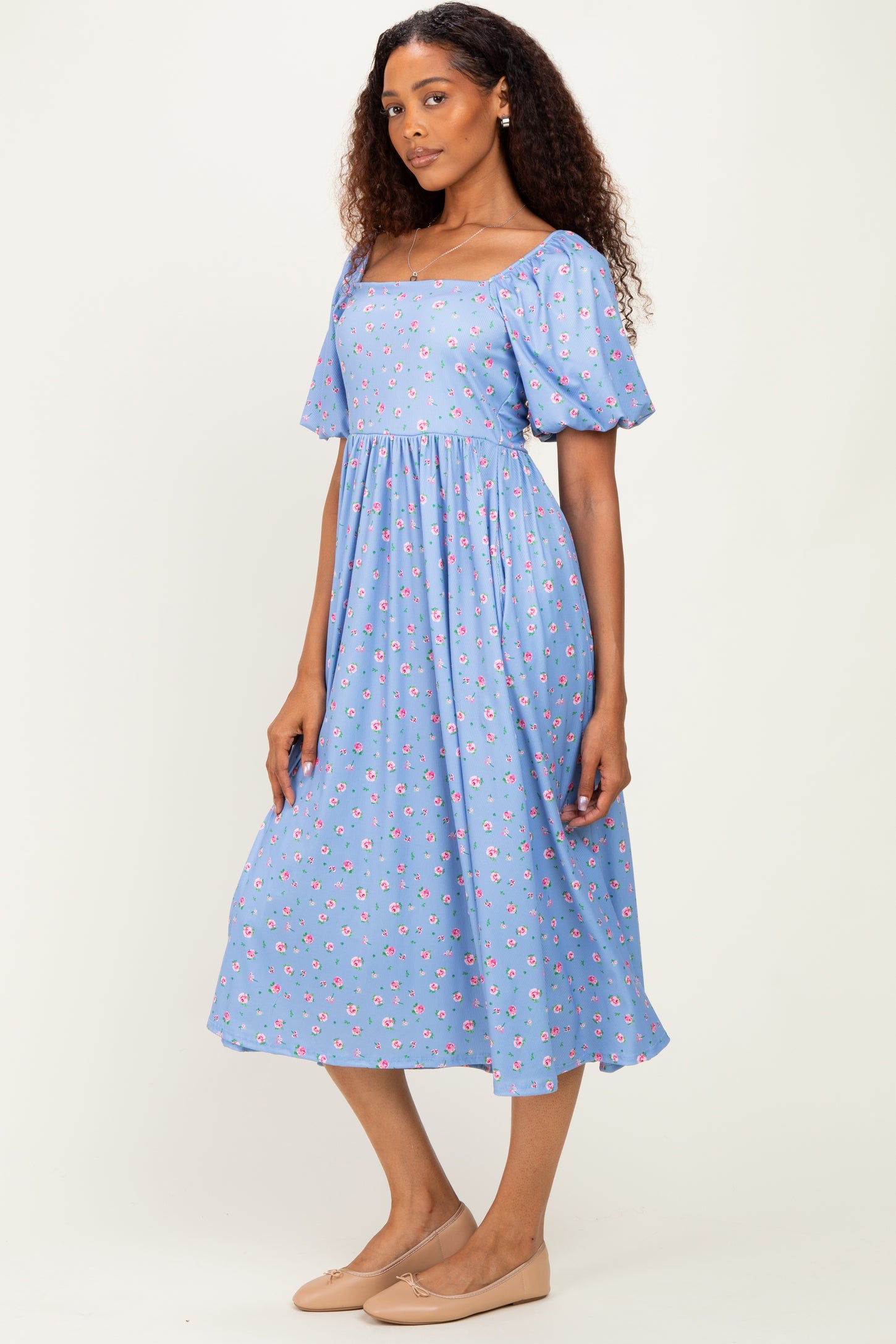 woman wearing a blue floral midi dress with puff sleeves and a square neckline