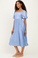 woman wearing a blue floral midi dress with puff sleeves and a square neckline