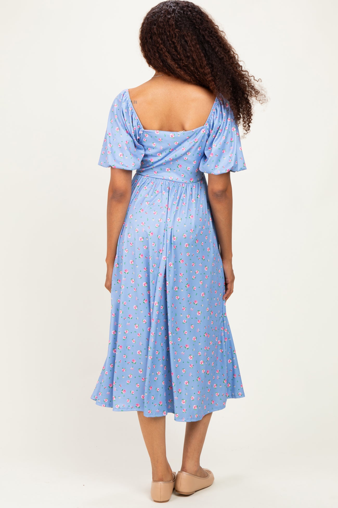 woman wearing a light blue floral midi dress with puff sleeves, showing the back and a relaxed fit