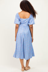 woman wearing a light blue floral midi dress with puff sleeves, showing the back and a relaxed fit
