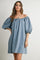 woman wearing a light blue off-the-shoulder denim dress with puff sleeves and a drawstring detail