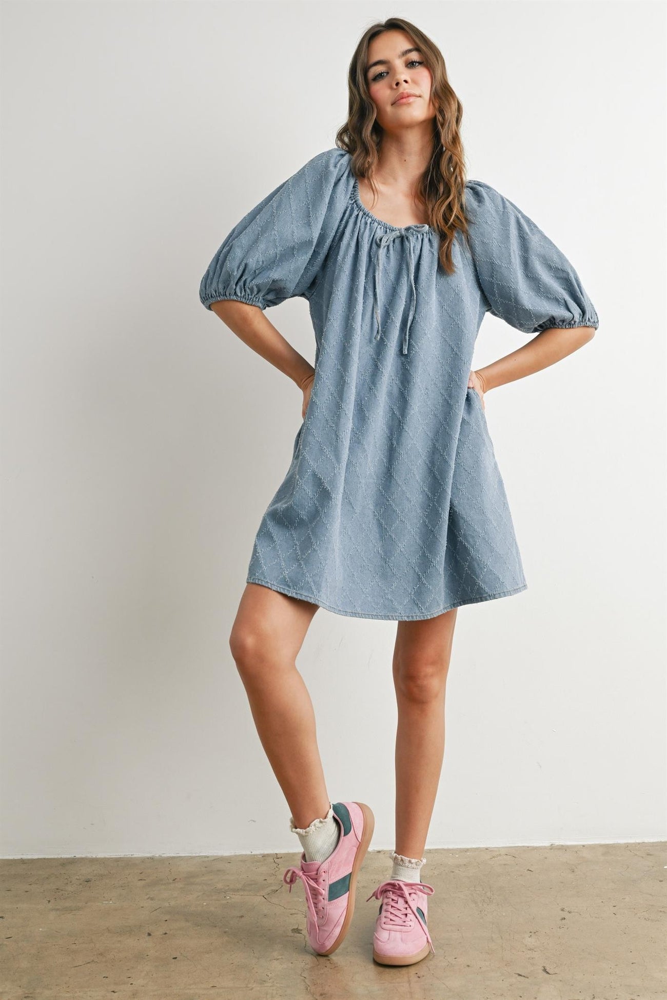 woman wearing a light blue puff sleeve dress with a square neckline and styled with pink sneakers