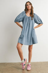 woman wearing a light blue puff sleeve dress with a square neckline and styled with pink sneakers
