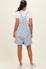 woman wearing a blue floral print overall romper with a white t-shirt underneath and white sneakers