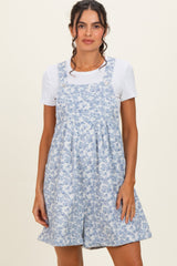 woman wearing a blue floral print overall dress with a white t-shirt underneath