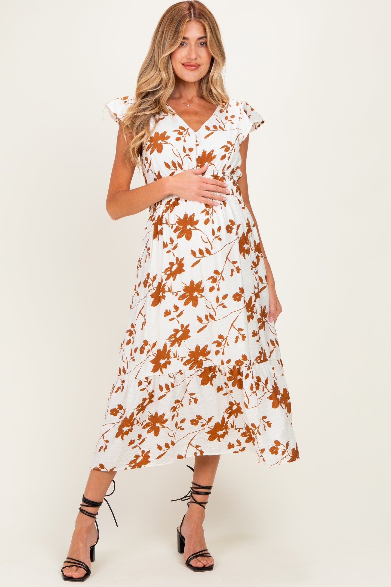 woman wearing a white floral maternity dress with short sleeves and a baby bump visible