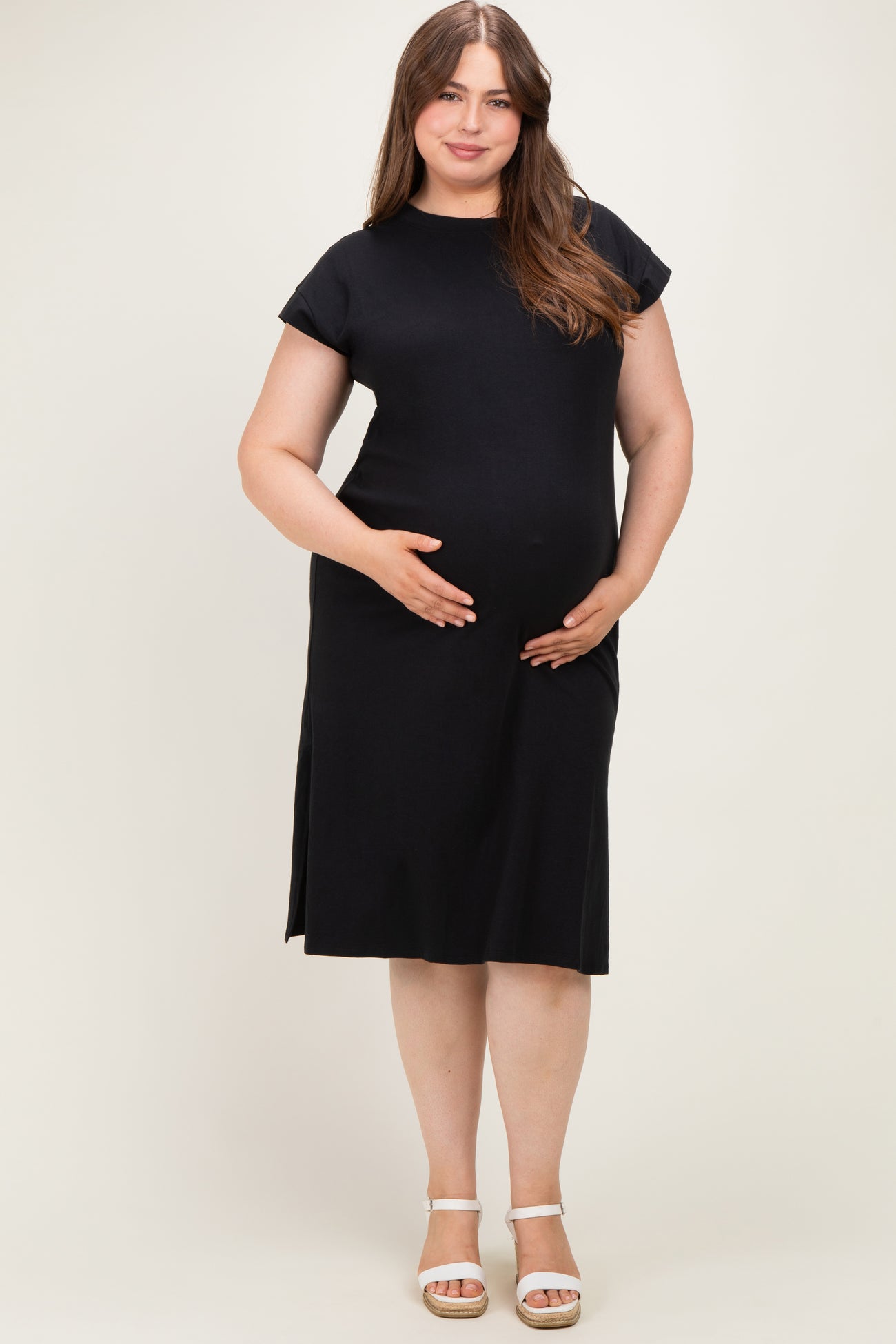 woman wearing a black short sleeve maternity dress with a relaxed fit, holding her baby bump
