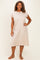 woman wearing a beige short sleeve plus size dress, standing with hands on hips and smiling at the camera