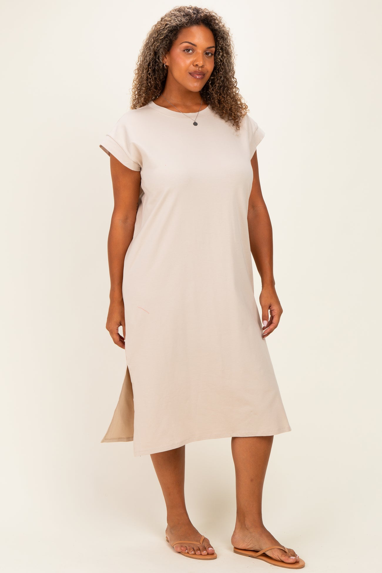 woman wearing a beige short sleeve plus size midi dress with side slits and a relaxed fit