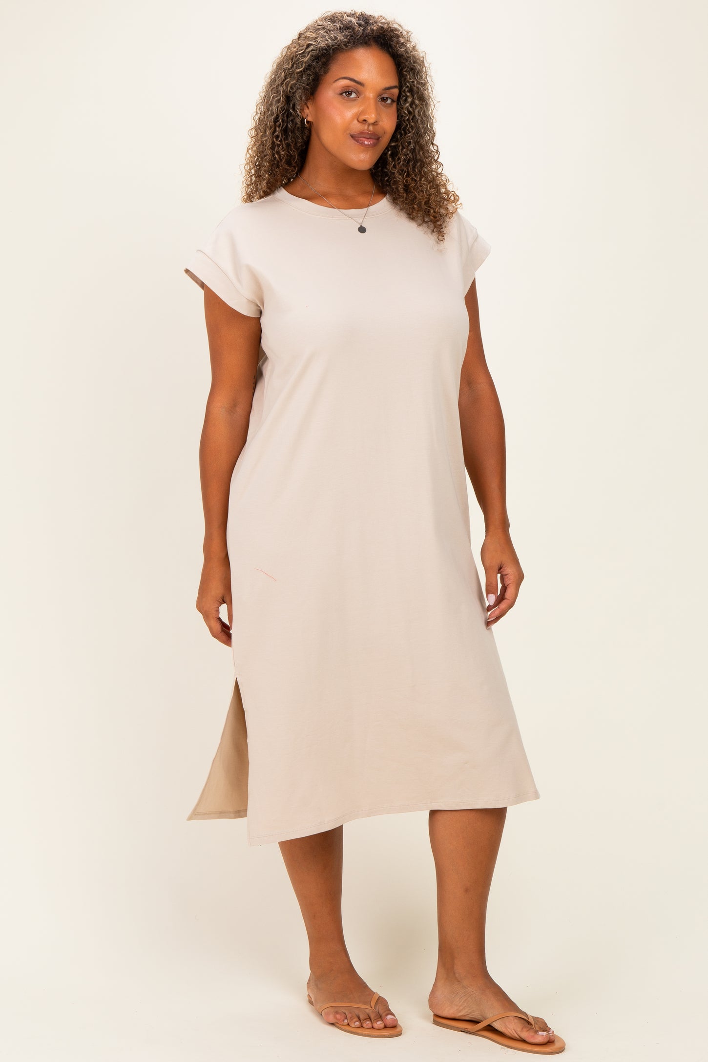 woman wearing a beige short sleeve plus size midi dress with side slits and a relaxed fit