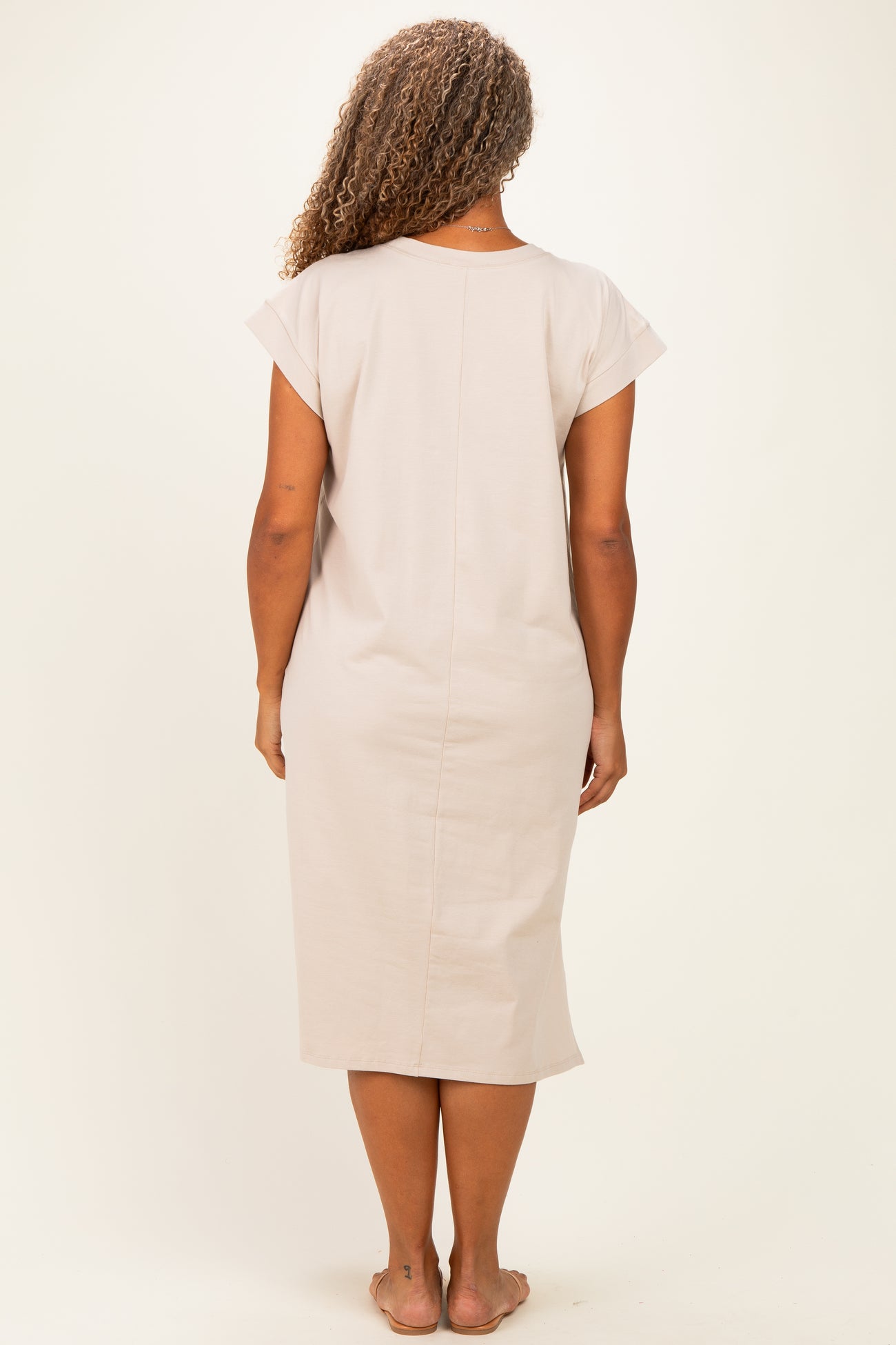 woman wearing a beige short sleeve plus size dress, viewed from the back