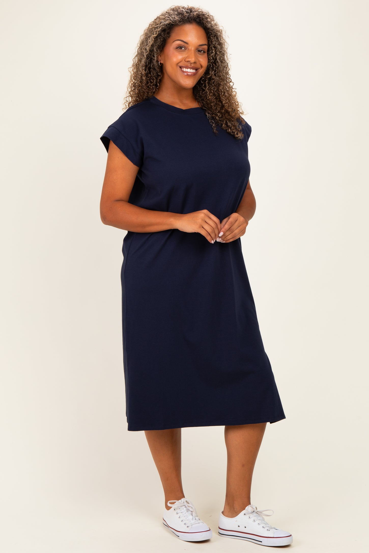 woman wearing a navy blue short sleeve plus size midi dress and white sneakers