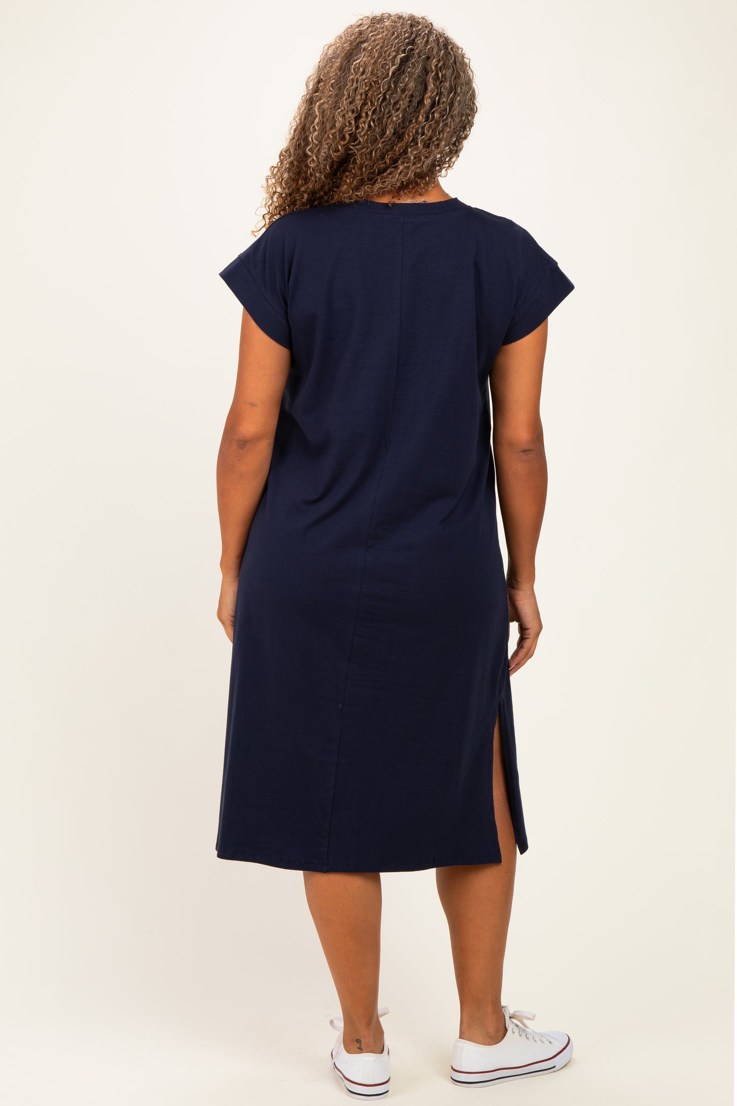 woman wearing a navy blue plus size t-shirt dress with cap sleeves and a side slit, shown from the back