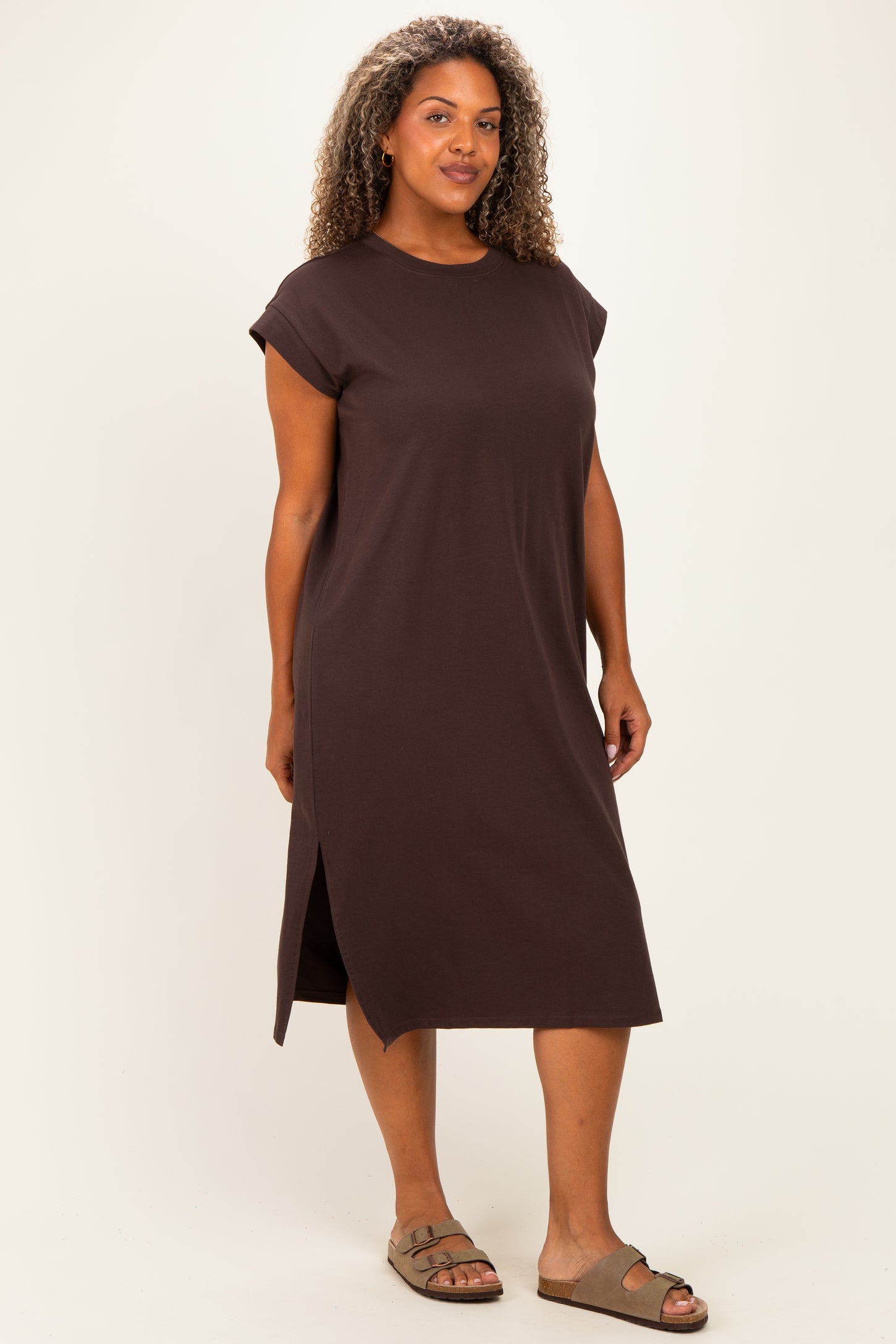 woman wearing a brown cap sleeve plus size dress with a side slit, standing against a neutral background