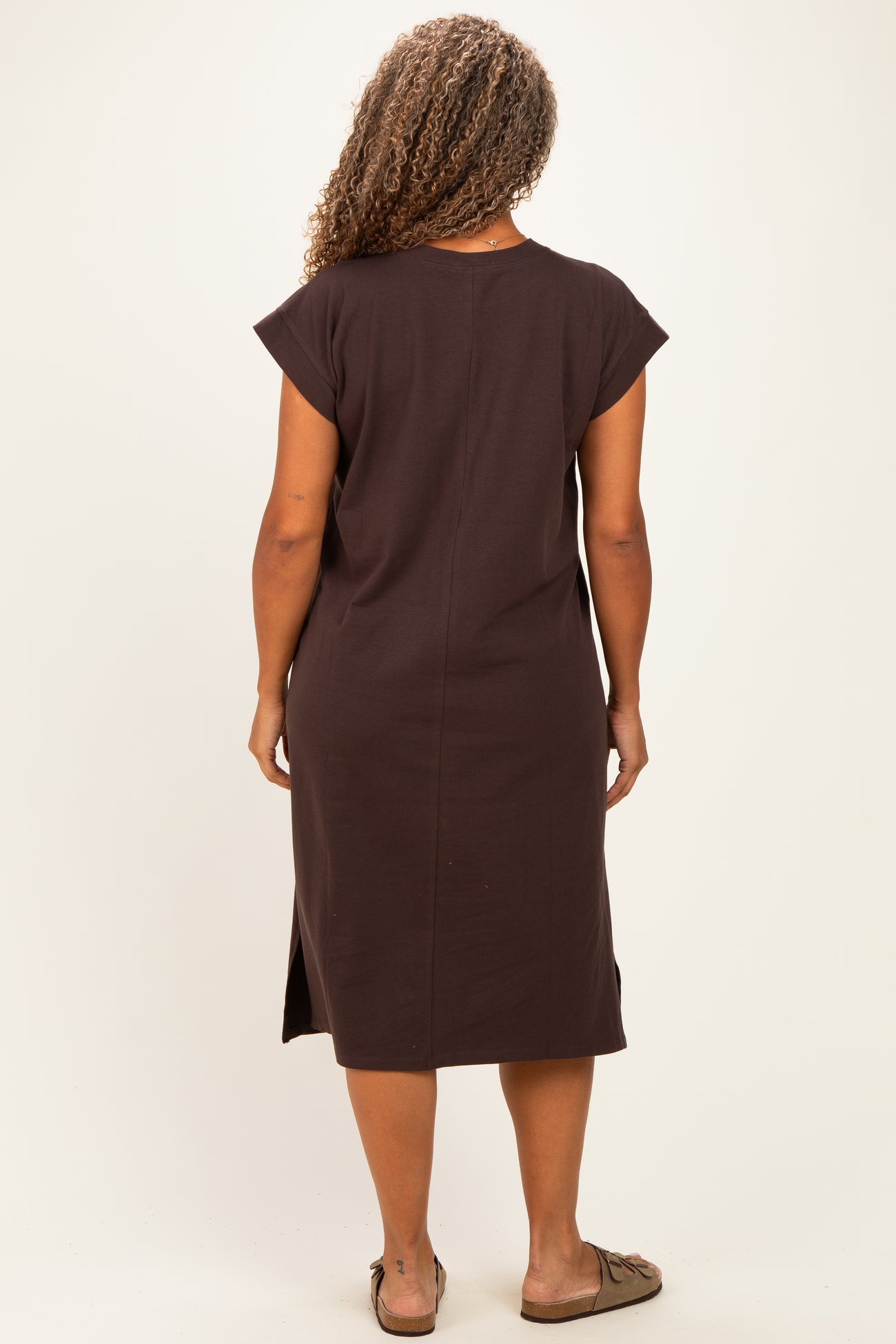 woman wearing a chocolate brown short sleeve plus size dress with side slits visible from the back