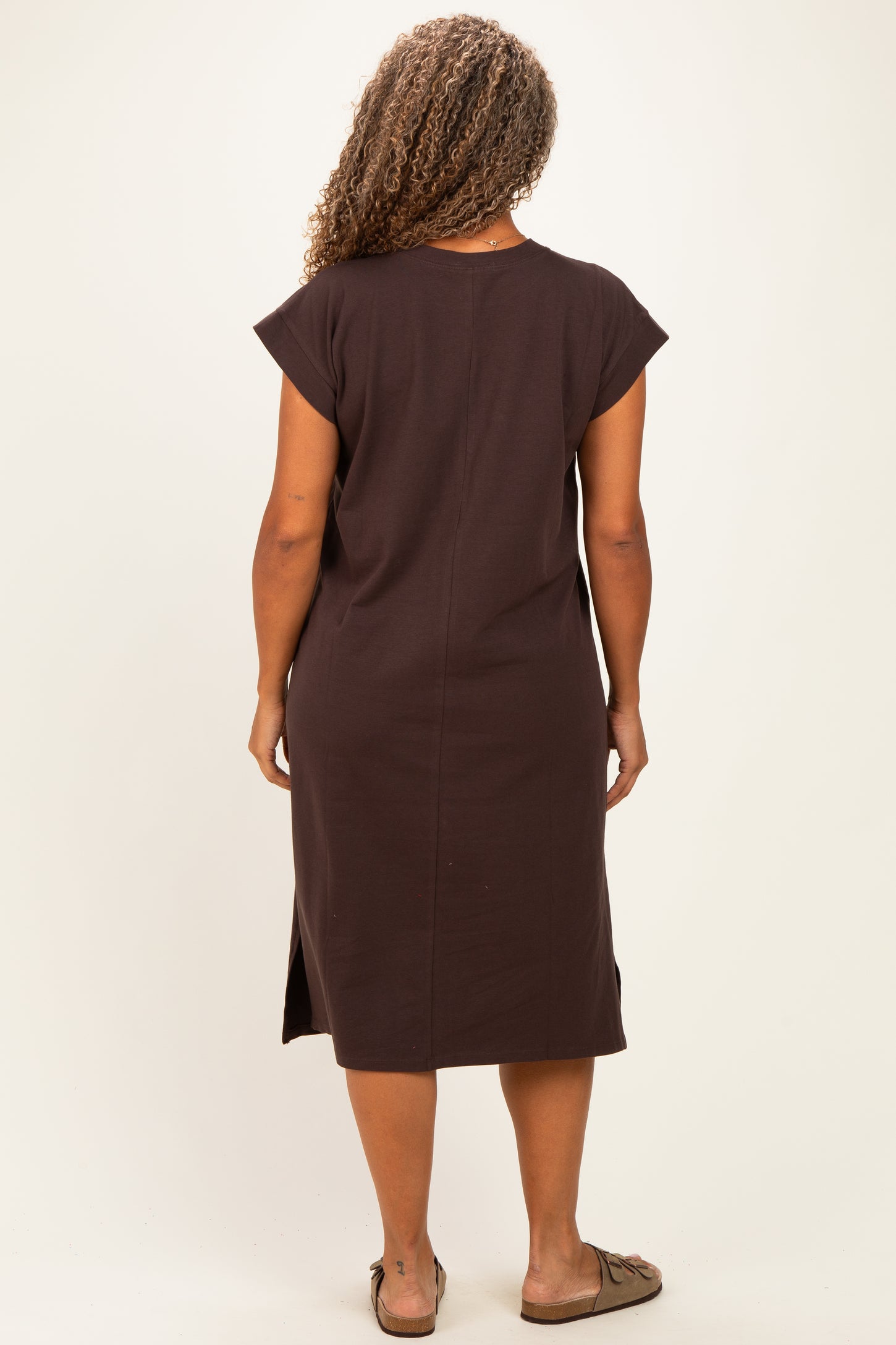 woman wearing a chocolate brown short sleeve plus size dress with side slits visible from the back