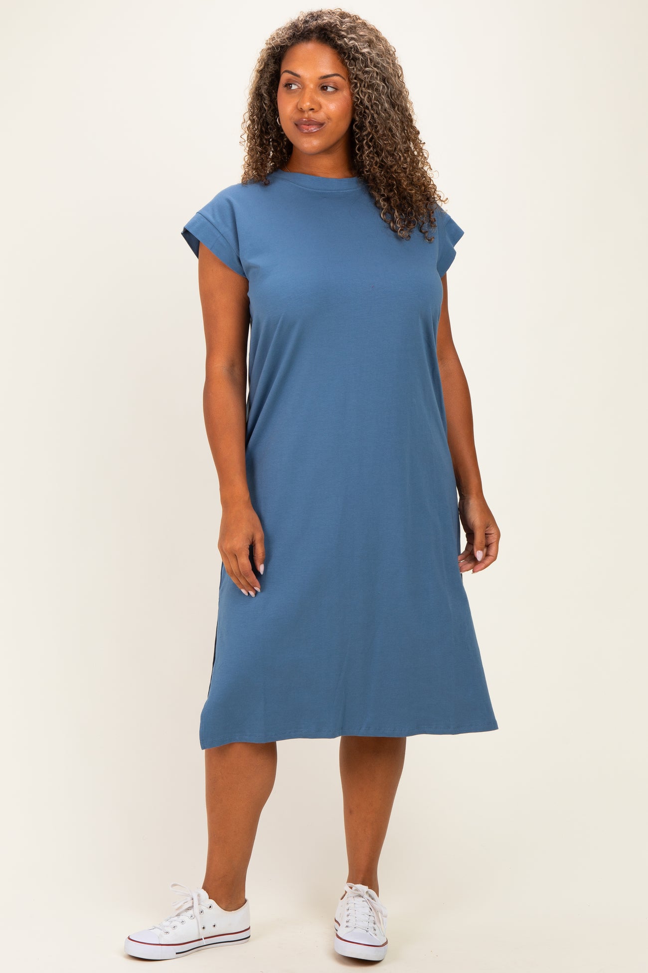 woman wearing a blue cap sleeve plus size midi dress with side slits and white sneakers