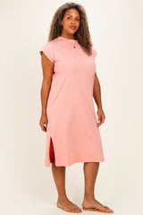 woman wearing a light pink cap sleeve plus size dress with side slits and standing on a neutral background