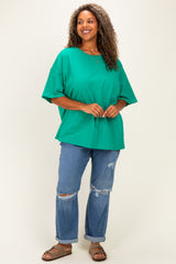 woman wearing an oversized green t-shirt paired with distressed blue jeans and sandals